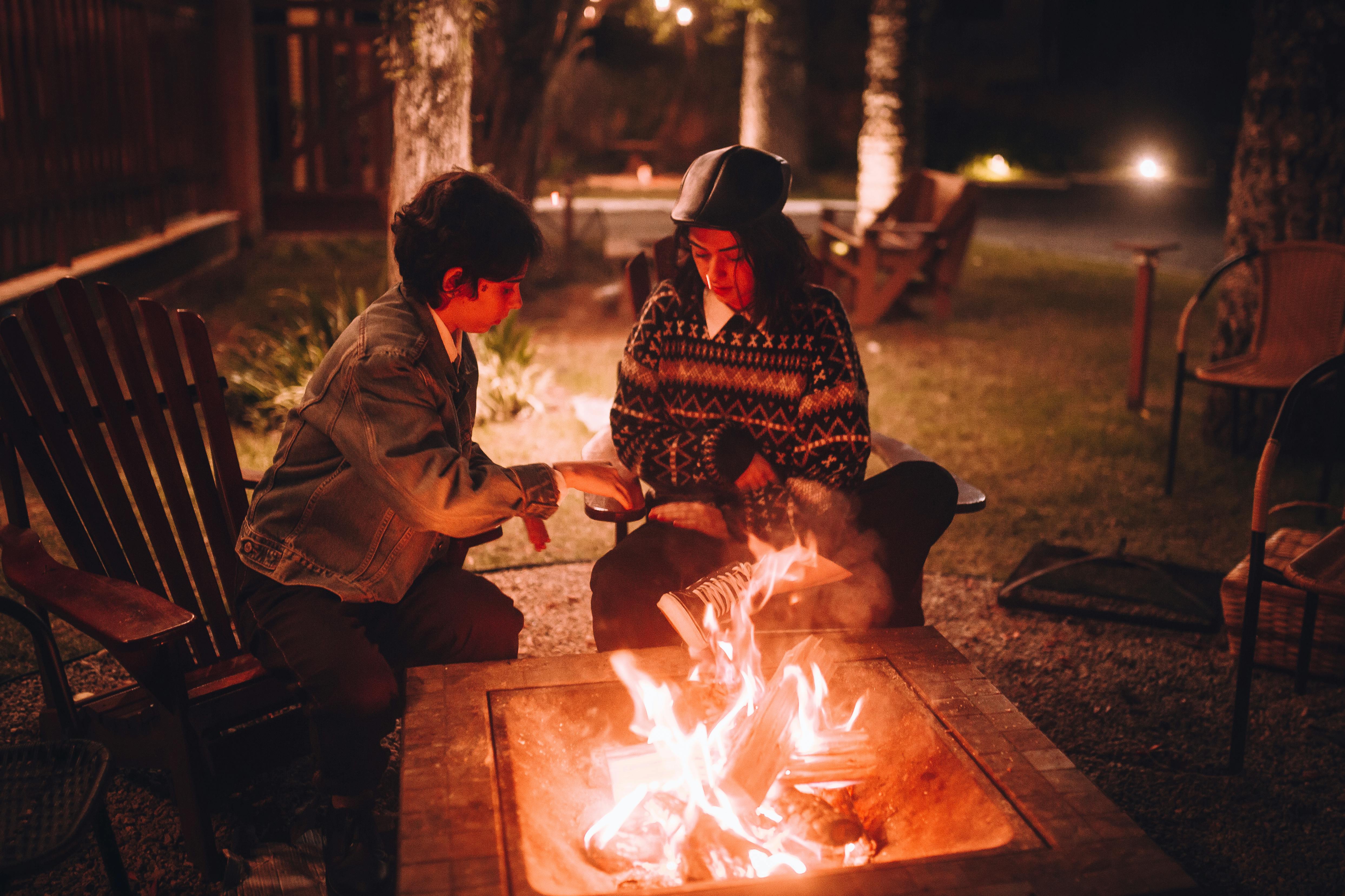 People gathered around a campfire circle at twilight, sharing stories under an open sky