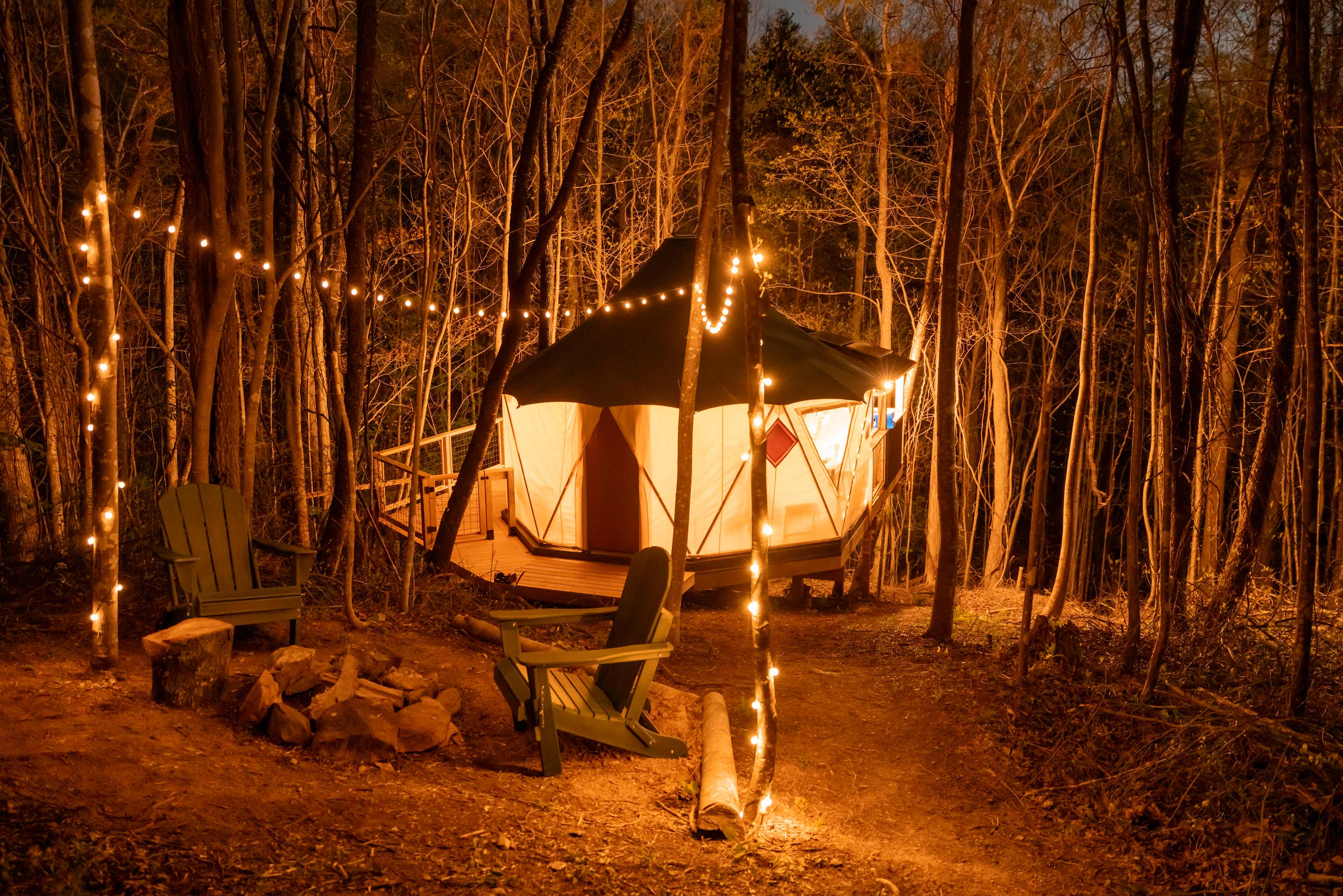 A canvas yurt glowing with warm light in a peaceful forest setting at dusk